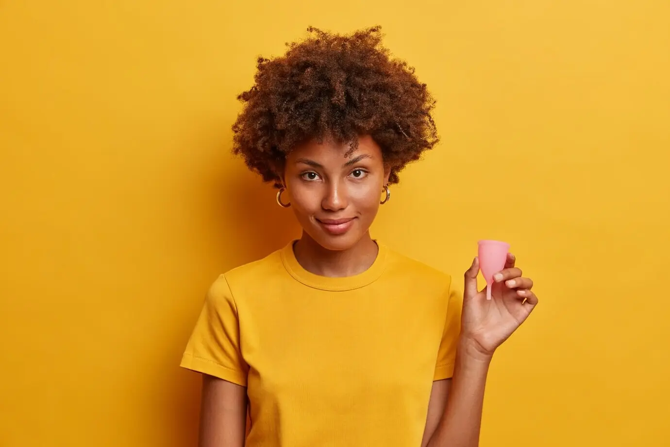 A confident woman presents a reusable silicone menstrual cup for women to use during periods as an alternative to tampons and sanitary napkins, explaining how to use this feminine hygiene product; the best internal protection.